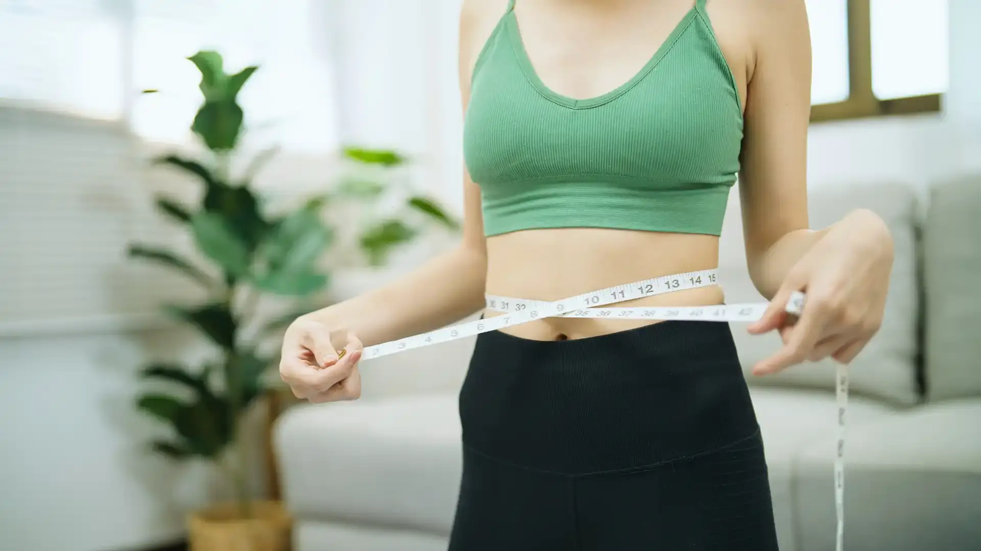 woman using measuring tape to measure waist size