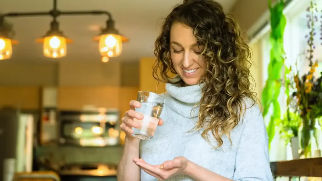 happy woman taking supplements with a glass of water