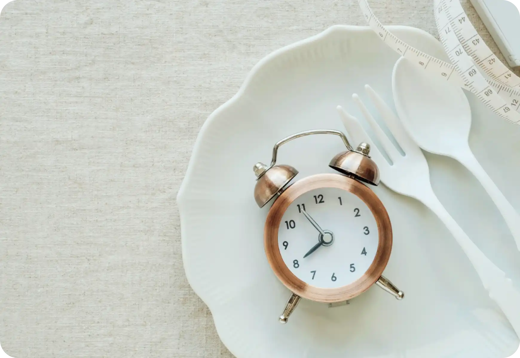 measuring tape, fork and alarm clock displayed on the plate