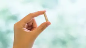 close-up of a hand gently holding a supplement capsule