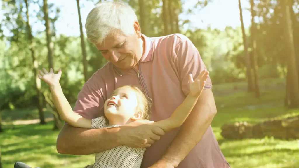 elderly man playing outdoors with a child on a sunny day, both smiling and enjoying the moment