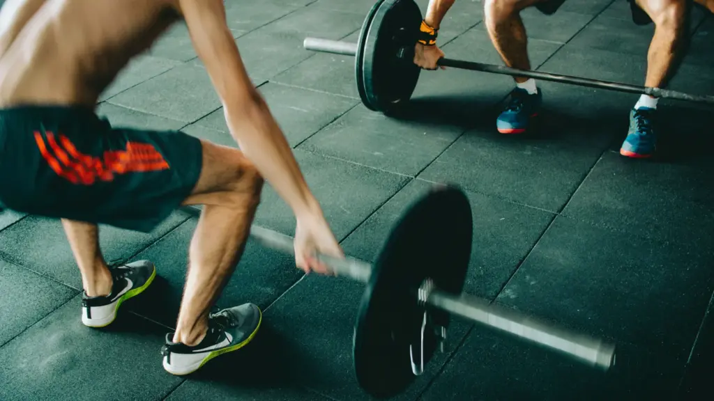 Two men lifting weights together in a gym, demonstrating strength training.