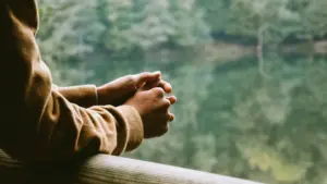 A man leaning casually against a fence, enjoying a peaceful view of nature
