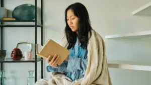 A woman comfortably seated in a cozy environment, reading a book